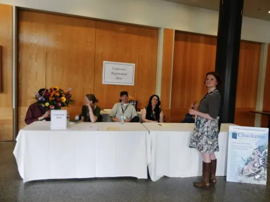 Current conference chair Anna Wolff checks in with the team at the info counter.